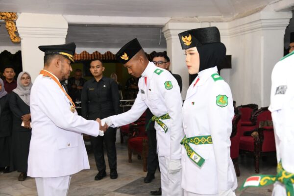Foto: Salah satu anggota Paskibraka Sumenep 2026 berjabat tangan dengan Bupati Sumenep, Achmad Fauzi Wongsojudo usai prosesi pengukuhan @Suaradara.com